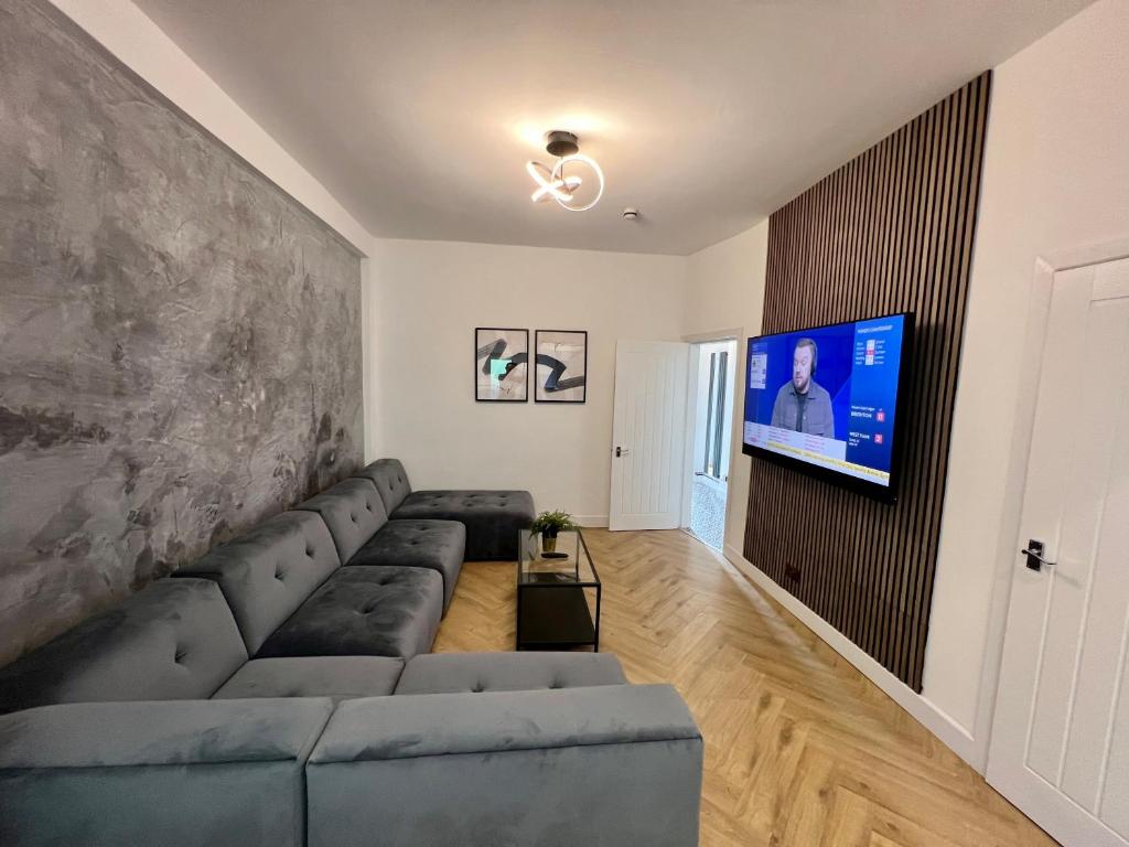 a living room with a couch and a flat screen tv at Modern City Centre Townhouse sleeps 10 & Parking in Manchester