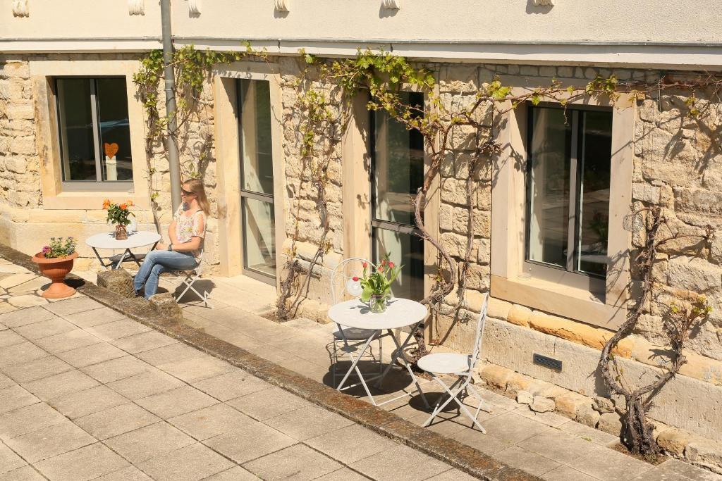 uma mulher sentada numa mesa em frente a um edifício em Plantagengut Hosterwitz em Dresden