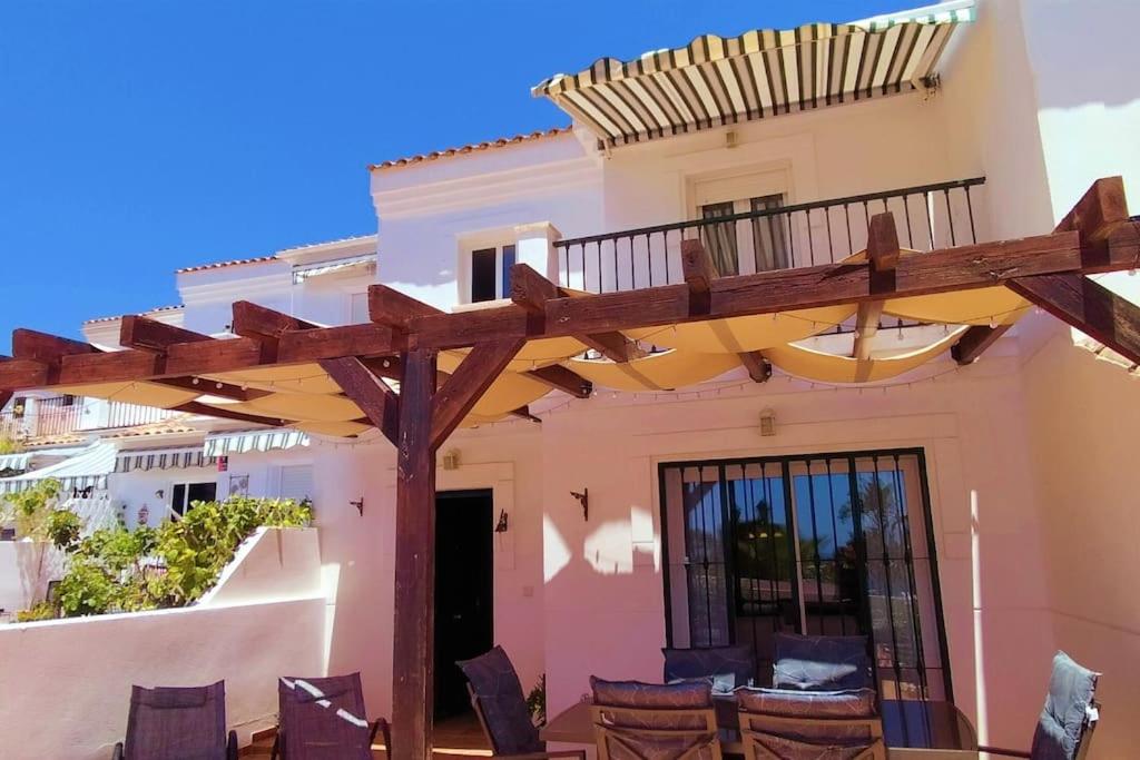 a wooden pergola in front of a house at Villa a 150 m de la playa. in Chilches