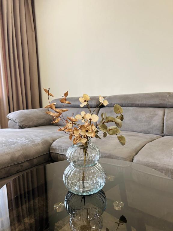 a glass vase with flowers on a glass table at Amot apartamentai in Telšiai