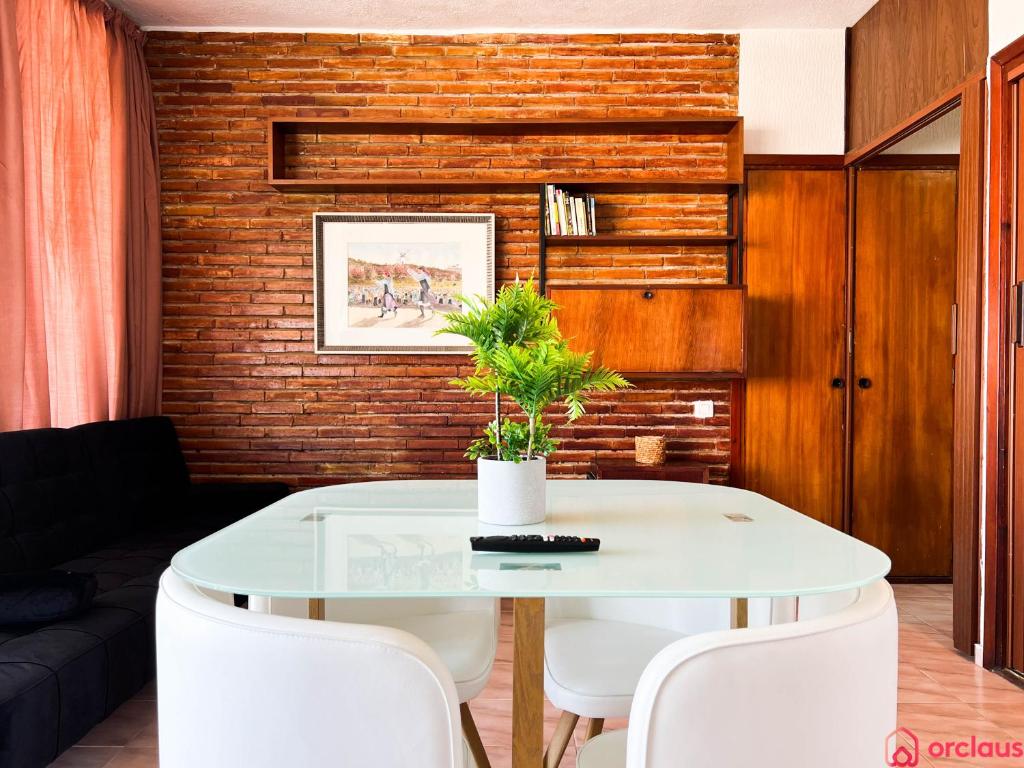 une salle à manger avec une table en verre et des chaises blanches dans l'établissement Oasis a 50m del Mar, à Grao de Castellón