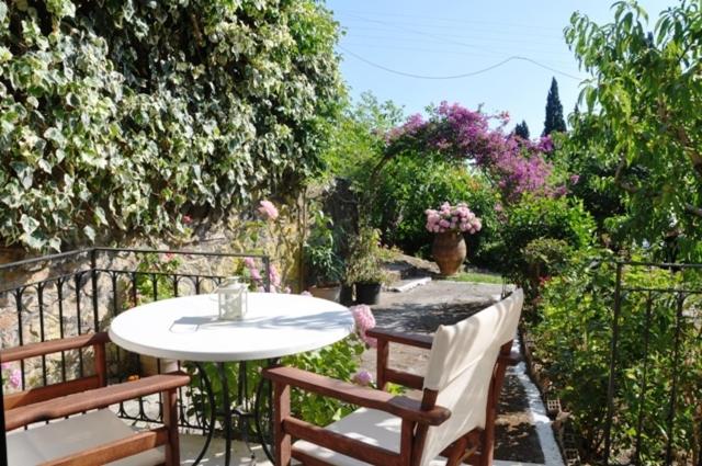 - une terrasse avec une table, 2 chaises et des fleurs dans l'établissement Taxi Driver Apartments, à Paleokastritsa