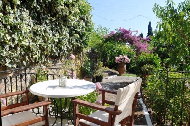a patio with a table and two chairs and flowers at Taxi Driver Apartments in Paleokastritsa