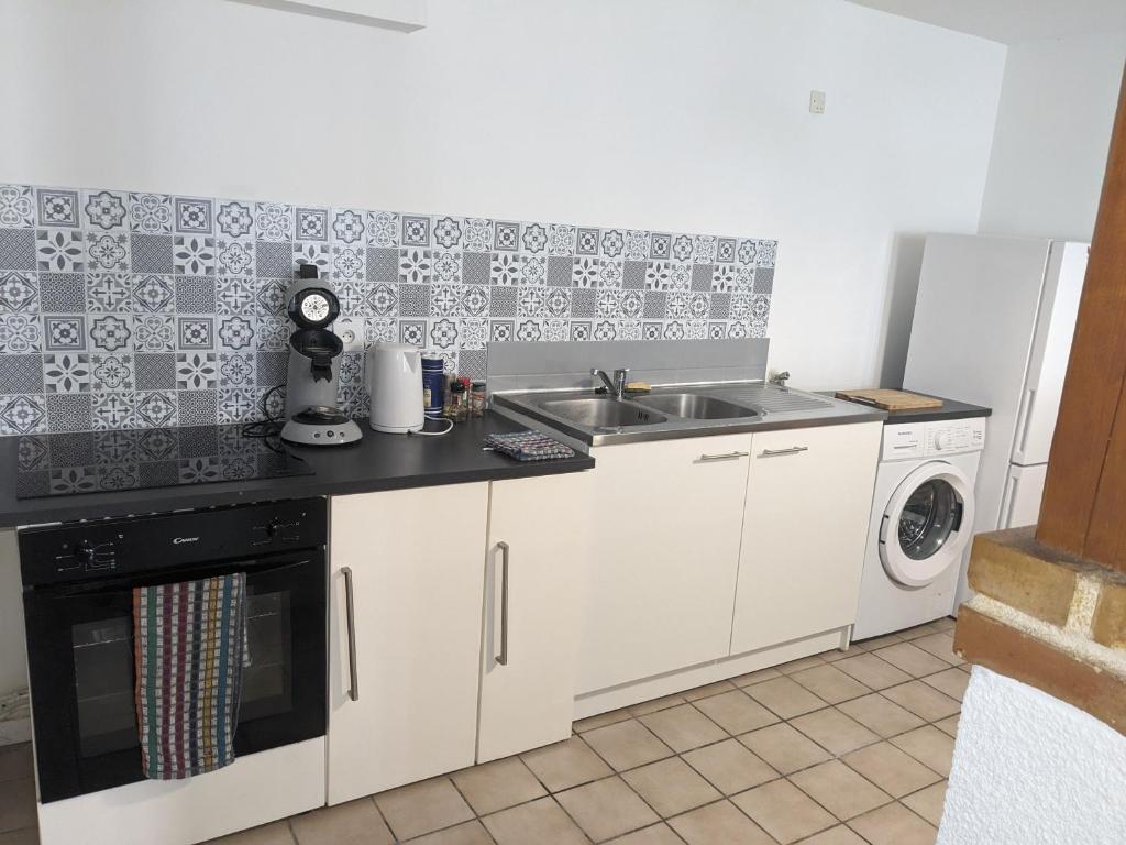 a kitchen with a sink and a washing machine at La rose des vents in Saint-Brisson-sur-Loire