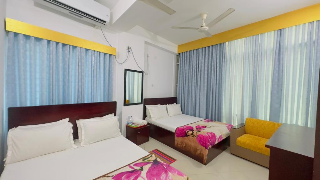 een hotelkamer met 2 bedden en een stoel bij Hotel City Panthapath in Dhaka