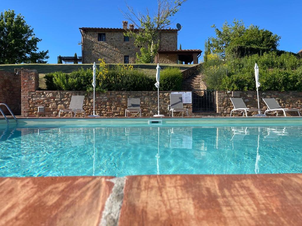 a swimming pool with chairs and a house in the background at Castellare Di Tonda Tuscany Country Resort & Spa in Montaione