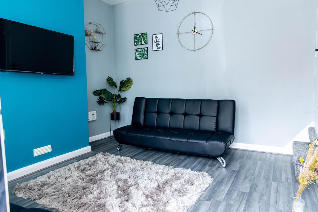 a black leather couch in a living room with a blue wall at Emerald Gem of Leeds with Great Location including Parking in Killingbeck