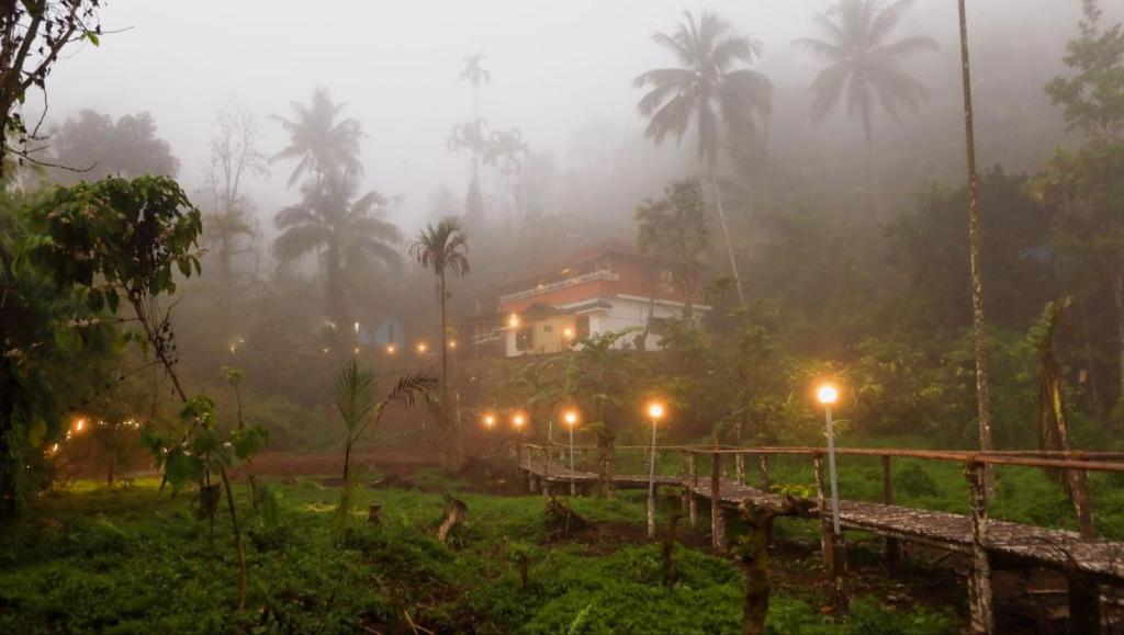 a house on a foggy hill with palm trees and lights at Mountain Manor in Vayittiri