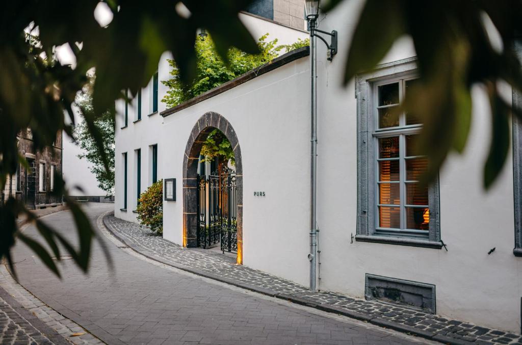 a cobblestone street in front of a white building at Hotel PURS in Andernach