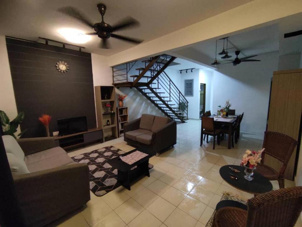 a living room with a couch and a dining room at Rumah teres 2 tingkat & 3 bilik in Pasir Gudang