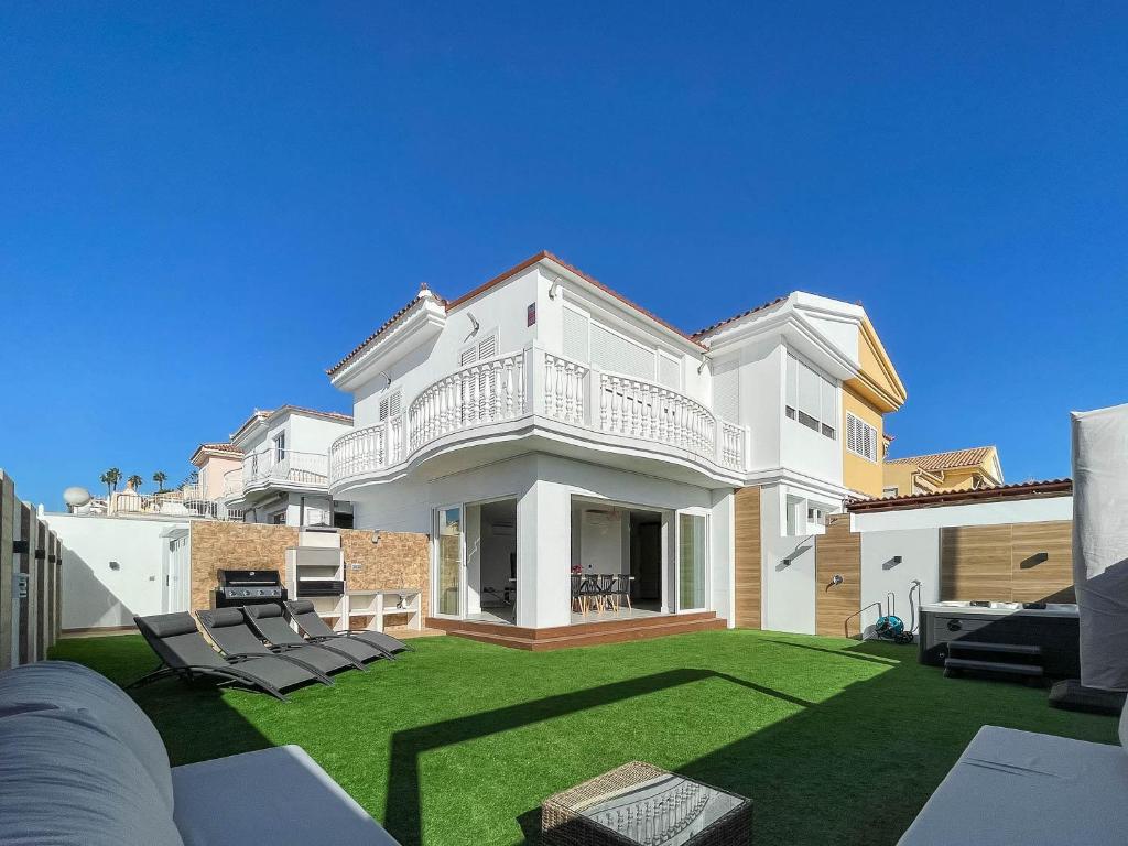 Una gran casa blanca con un patio con sillas. en Villa Sofía Maspalomas, en San Bartolomé