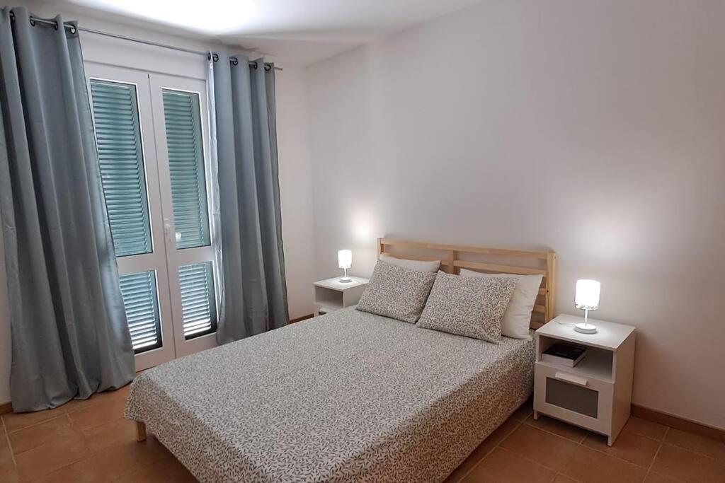una camera da letto con un letto con due comodini e finestre di Casa das Lombas a Vila Baleira