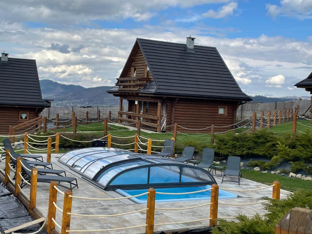 a house with a swimming pool in front of a house at Domki Zagroda Domek z bala z basenem in Słopnice