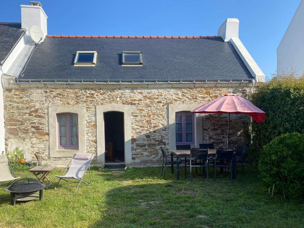 une maison avec une table, des chaises et un parasol dans l'établissement Charmante maison en pierre avec jardin à Bangor, à 1500 m de la plage de Vazen - FR-1-418-157, à Bangor