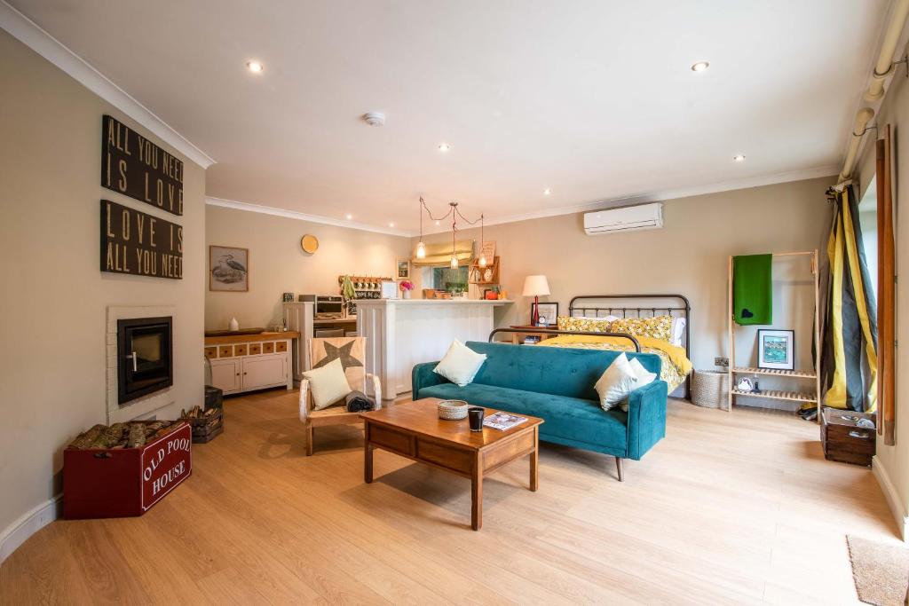 a living room with a blue couch and a bed at Granby Estate The Old Pool House in Bradford on Avon