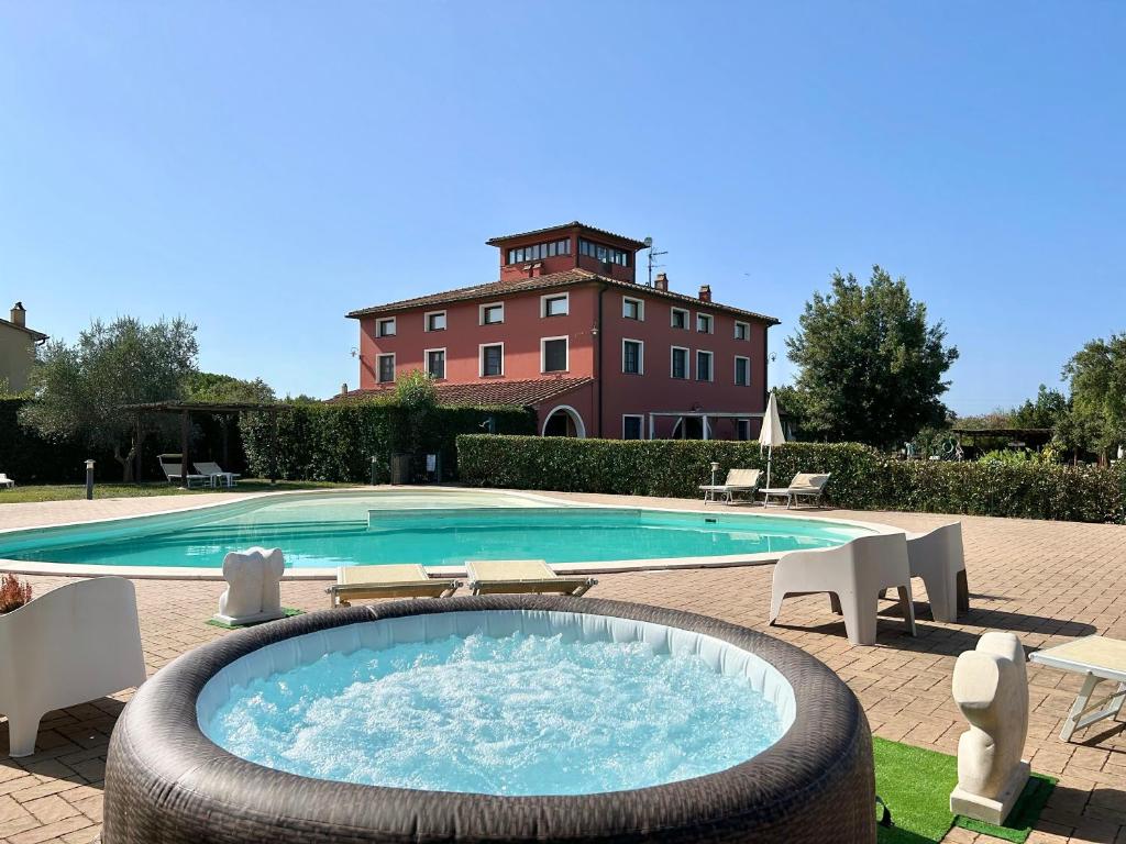 una grande piscina con un edificio sullo sfondo di Resort Il Casale Bolgherese - by Bolgheri Holiday a Bolgheri