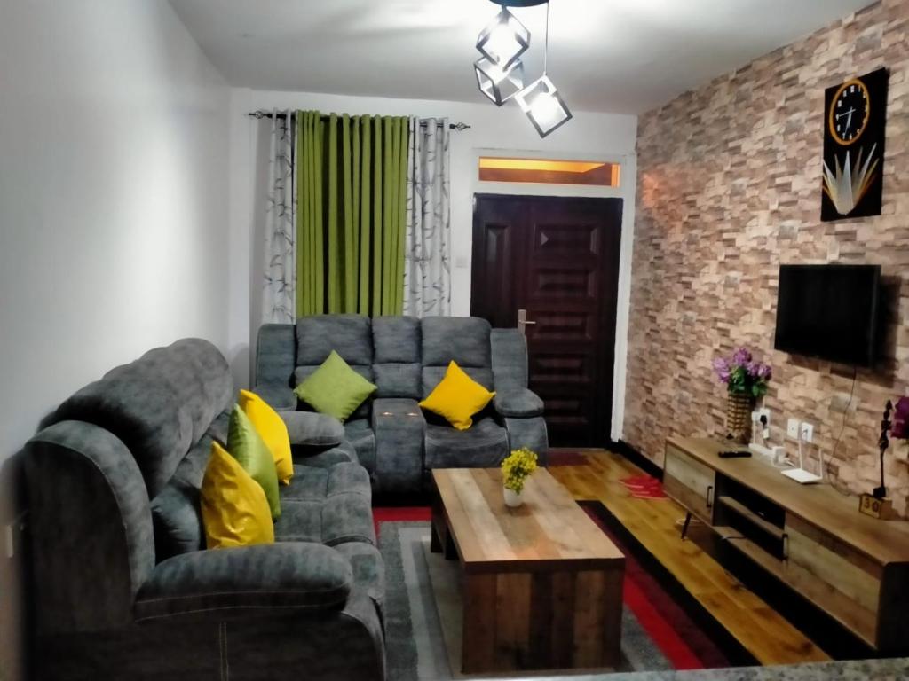 a living room with a gray couch and yellow pillows at Two Bedrooms Furnished Apartment in Nakuru in Nakuru