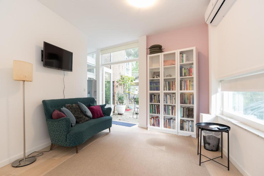 a living room with a green chair and a book shelf at B&B Amsterdam West in Amsterdam