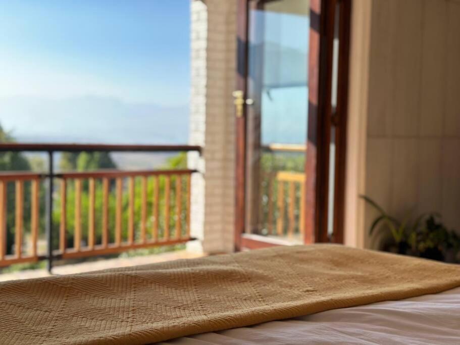 a blanket on a bed in front of a balcony at Clarens Tranquil Mountain Villa in Clarens