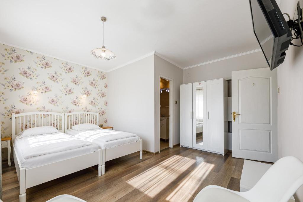 1 dormitorio con 2 camas blancas y papel pintado con motivos florales en Pensiunea Bella, en Arad
