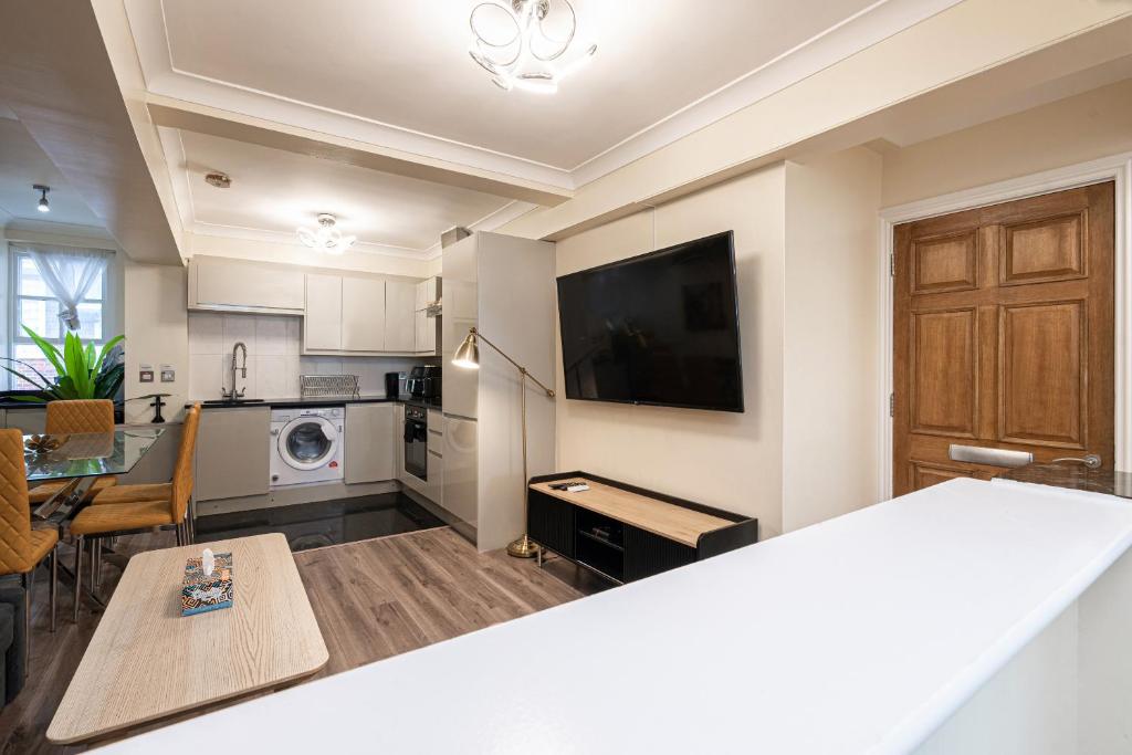 Gorgeous 4 bedrooms apartment near Hyde Park and Oxford St في لندن: مطبخ وغرفة معيشة مع طاولة وتلفزيون