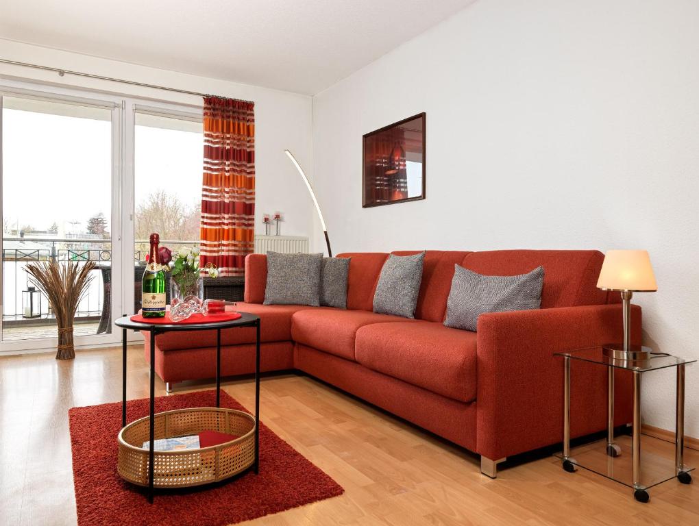 a living room with a red couch and a table at Landhaus Residenz Kirchsee Ostseetraum in Insel Poel
