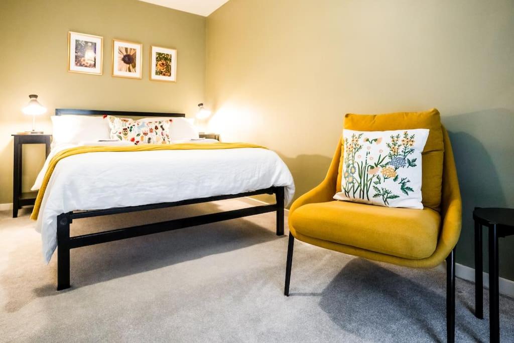 a bedroom with a bed and a yellow chair at Artist's Garden on Wolsey Island in Leicester