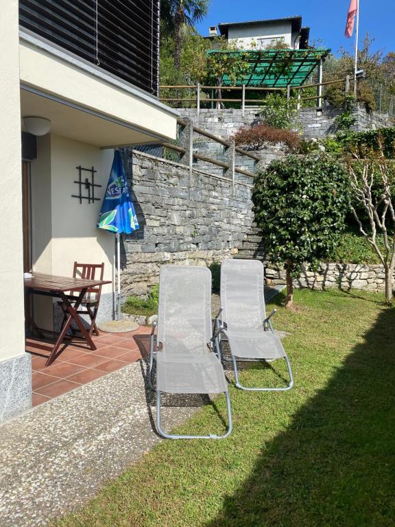 zwei Stühle, einen Tisch und einen Regenschirm in einem Hof in der Unterkunft Casa Vignole-Badasci in Orselina