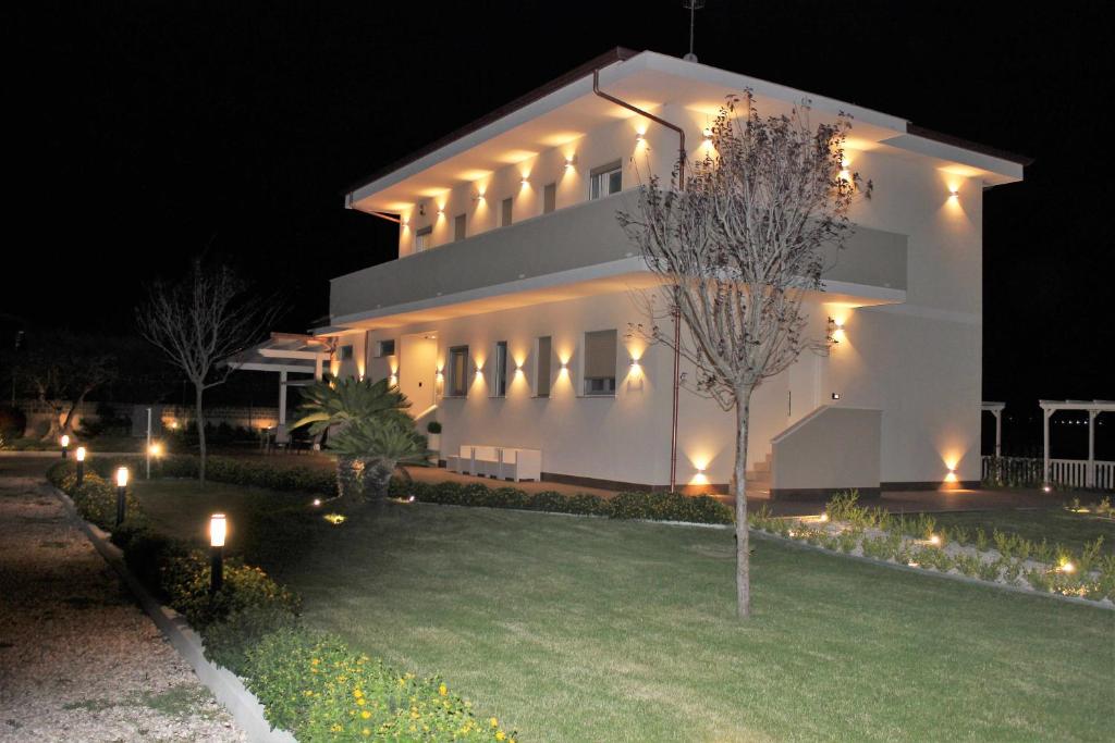 een wit gebouw met lichten op een tuin 's nachts bij Villa Zefiro Suites e Events in Battipaglia