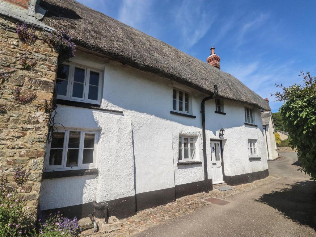 a white cottage with a thatched roof at Brewers Cottage in Kings Nympton