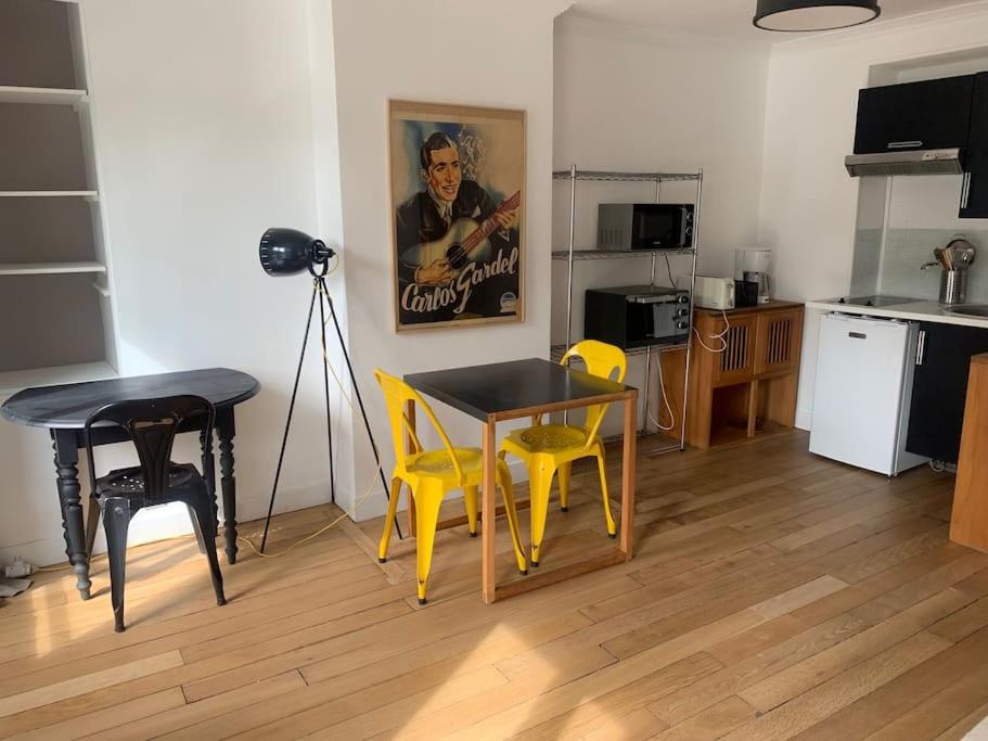 a living room with a table and chairs and a kitchen at St ouen centre 20mn de châtelet Ligne 14 in Saint-Ouen