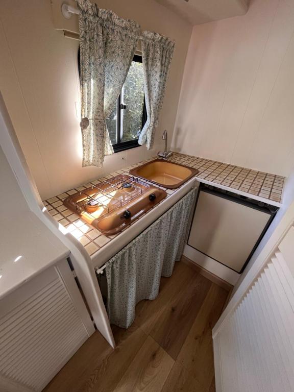 La salle de bains est pourvue d'un lavabo et d'une fenêtre. dans l'établissement Sympathique camping car J9, à Avesnelles