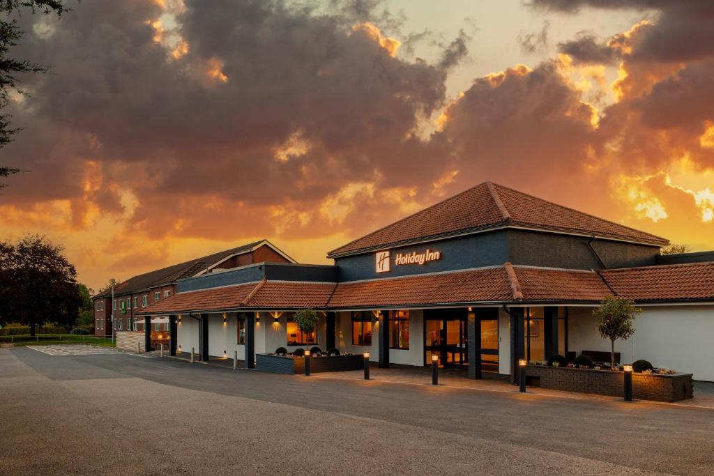 a building with a sunset in the background at Holiday Inn High Wycombe M40, Jct.4, an IHG Hotel in High Wycombe