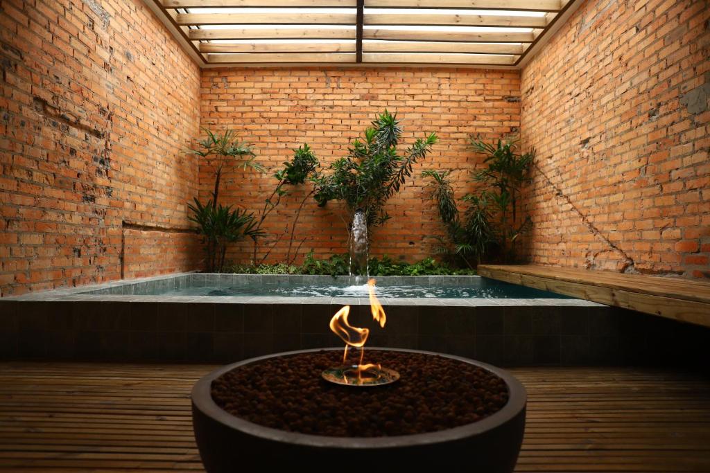 a hot tub in a brick wall with a fire pit at LUV Gardens Motel - Adults Only in Caxias do Sul