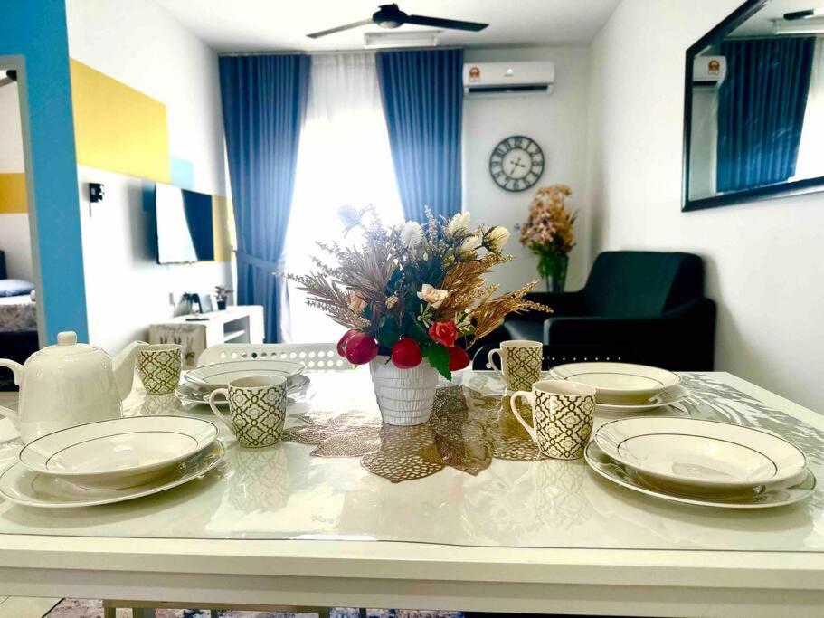 einen Esstisch mit Tellern und Blumen darauf in der Unterkunft AF Homestay 2 Bedrooms 15mins to KLIA Free Wifi Netflix in Sepang