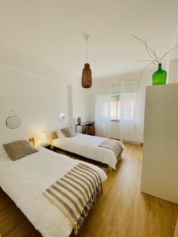 Habitación blanca grande con 2 camas y suelo de madera. en Bright modern 3 BR in Portimao downtown, en Portimão