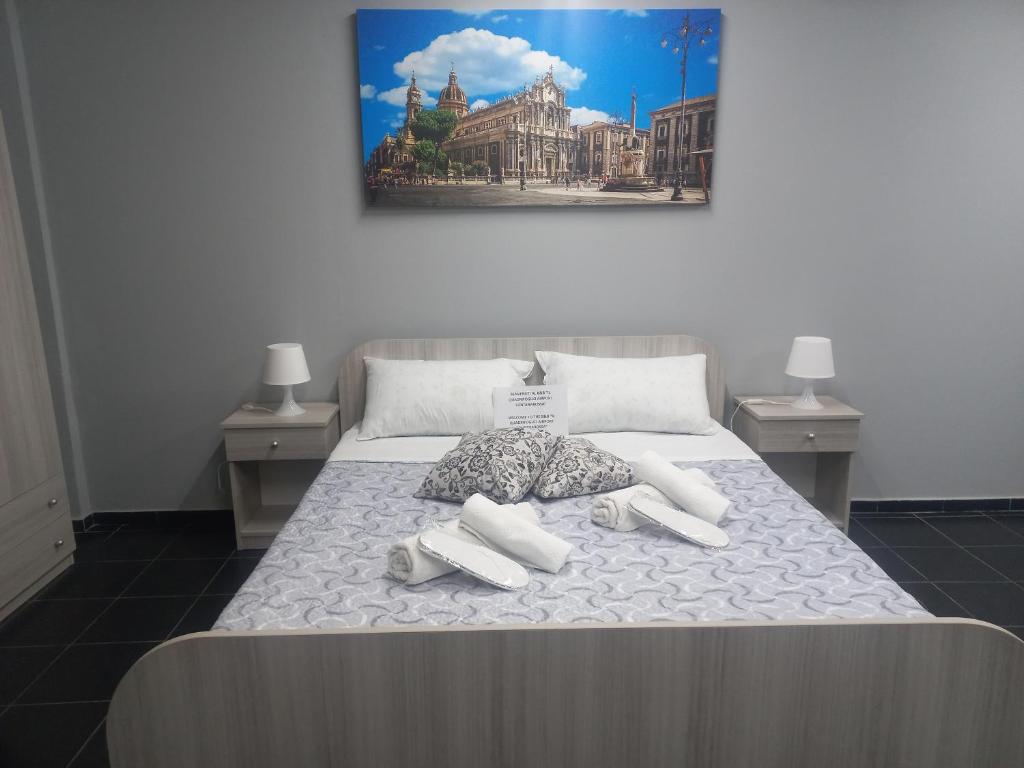 uma cama com almofadas brancas e um quadro na parede em B&B Il Quadrifoglio Airport Fontanarossa em Catânia