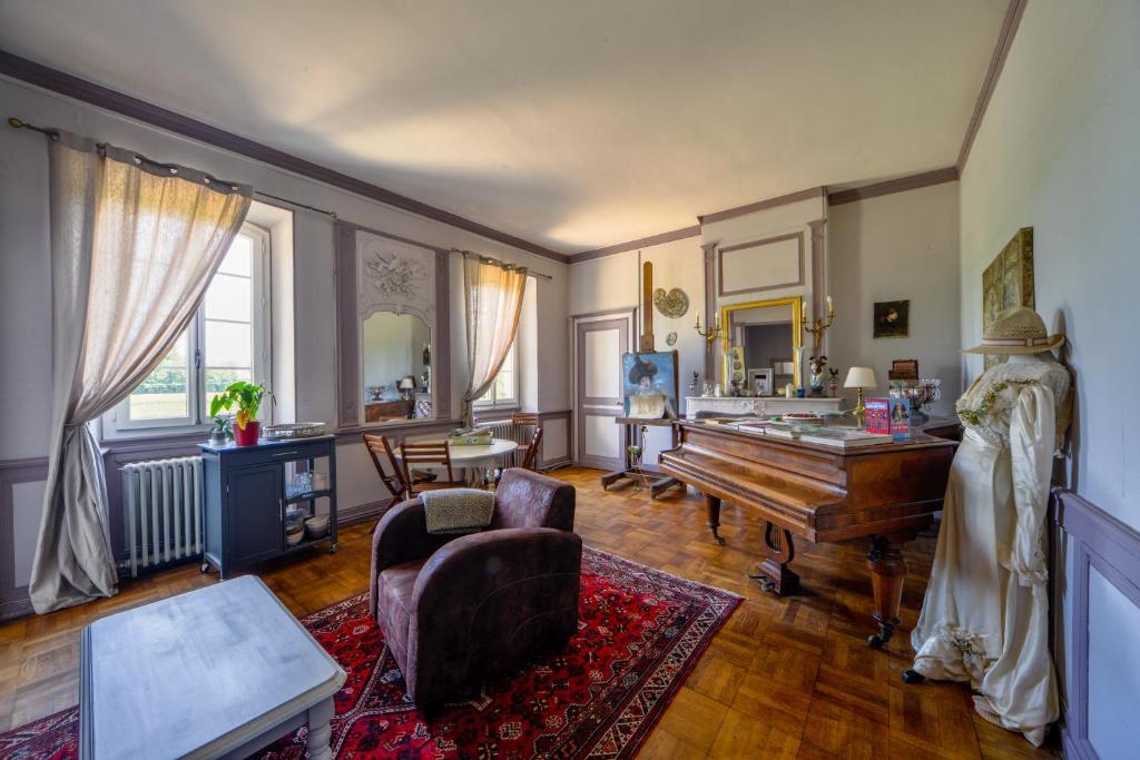 sala de estar con piano y mesa en Petit Gîte de Villecomte, en Sainte-Solange