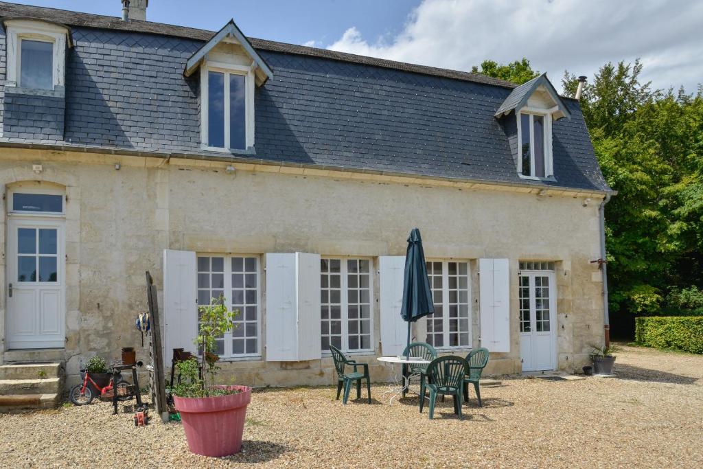 uma casa com uma mesa e cadeiras e um guarda-sol em Petit Gîte de Villecomte em Sainte-Solange