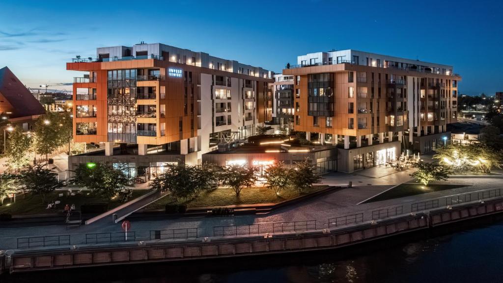 a group of buildings next to a river at night at Apartamenty Sun & Snow Stara Stocznia in Gdańsk
