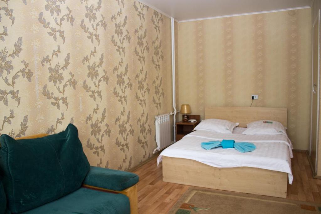 um quarto com uma cama e um sofá verde em Валенсия em Petropavl