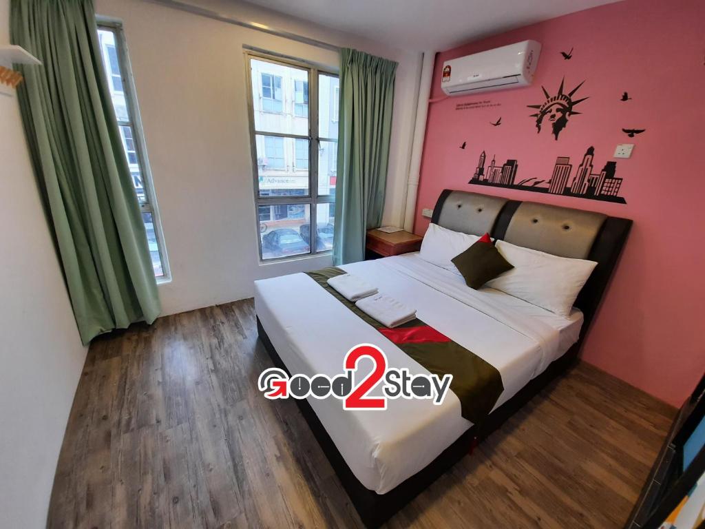 a bedroom with a bed with a pink wall at Good2Stay Hostel in Melaka