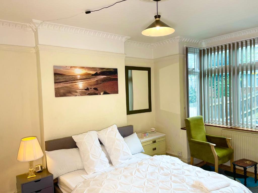 a bedroom with a white bed and a green chair at E-Sky Homes in South Norwood