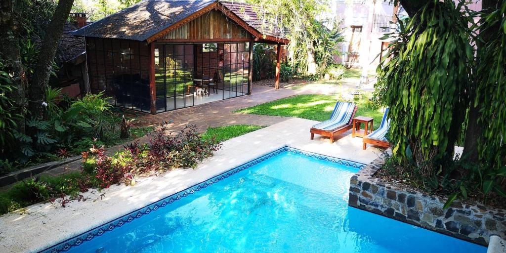 a swimming pool with two chairs and a gazebo at Rincón Escondido B&B in Puerto Iguazú