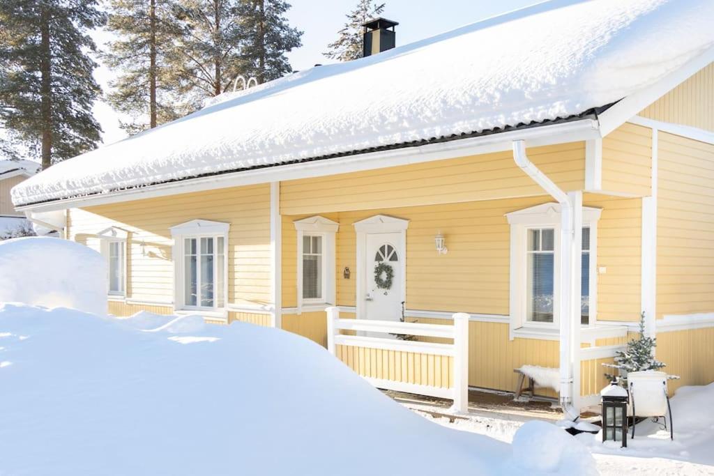 a yellow house with snow in front of it at Arctic Circle Home close to Santa`s Village in Rovaniemi