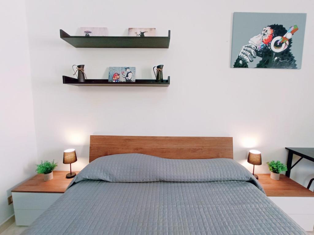 sypialnia z łóżkiem i 2 półkami na ścianie w obiekcie Le Stanze del Corso w mieście Ascoli Piceno