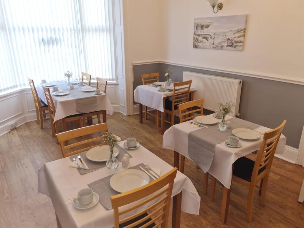 um restaurante com mesas e cadeiras com toalhas de mesa brancas em The Chimes em Bridlington