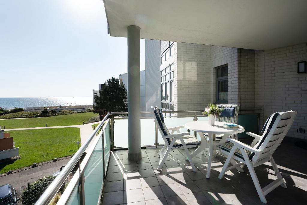 balcón con mesa, sillas y vistas al océano en Villa am Hang Wohnung 11 en Grömitz