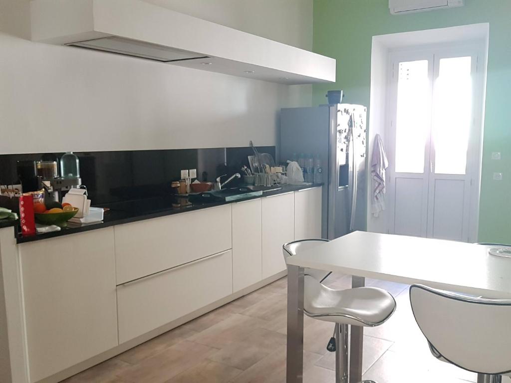 une cuisine avec des armoires blanches et une table blanche dans l'établissement Grand Standing, à Ajaccio