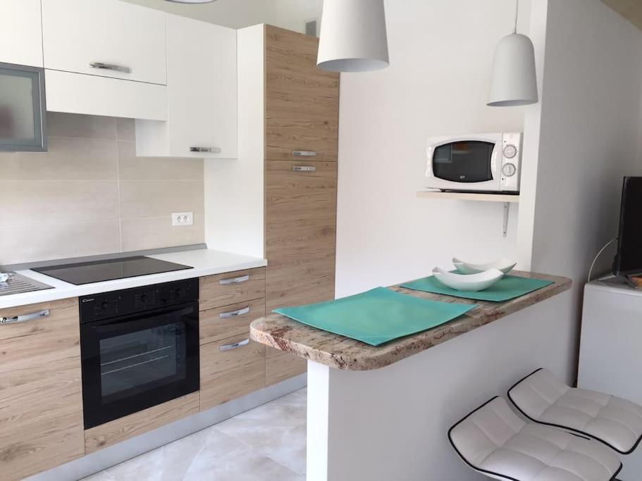 une cuisine avec des appareils électroménagers blancs et un comptoir avec un tabouret dans l'établissement Studio centre ville entièrement rénové au calme, à Menton